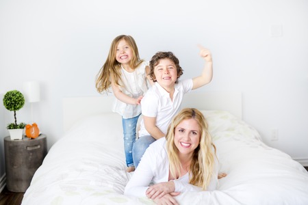 Portrait of a happy mother and her children lying on a bedの写真素材