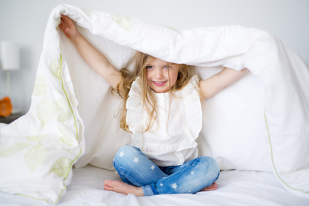 Adorable little girl waked up in her bedの写真素材