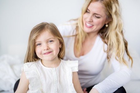 Cute little girl and her mother lying on a bedの写真素材