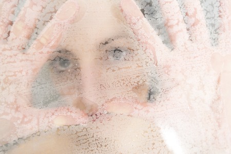 Stressed woman leaning on weeping glass shower doorの写真素材
