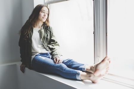 Teenager girl sitting on windowの写真素材