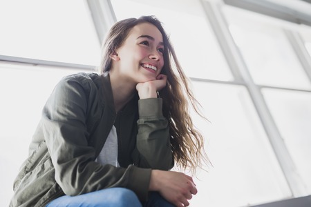 Teenager girl sitting on windowの写真素材