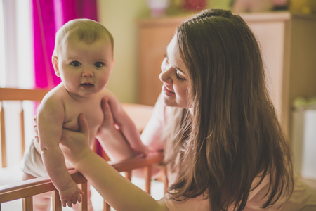 portrait of a happy mother with cute baby in cribの写真素材