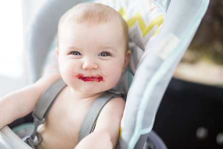 Baby girl sitting in high chair for eatingの写真素材