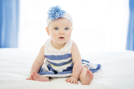 Baby girl in white bedding at home look niceの写真素材