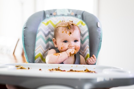 Little baby eating her dinner and making a messの写真素材