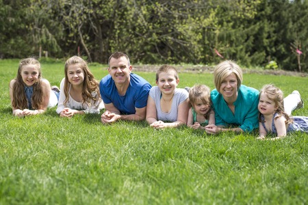 Happy family members lay in green grass outdoorsの写真素材