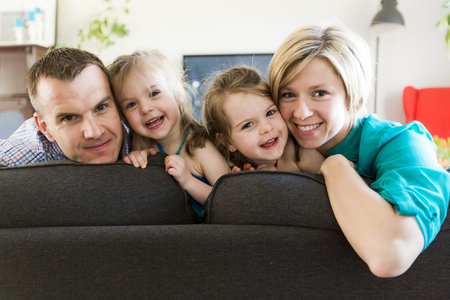happy family with twin kids on the couchの写真素材