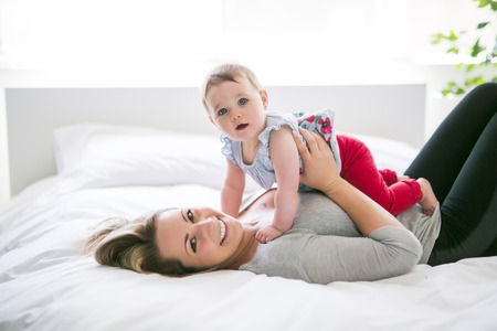Pretty baby sit on mom in silk bed