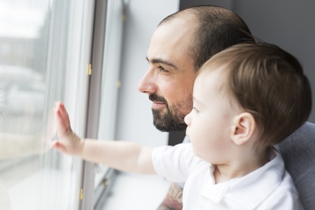 Father and son indoor near the window.の写真素材