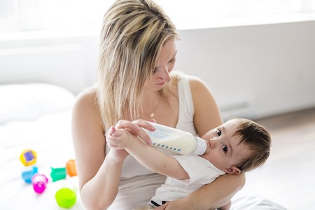 Mother holding and feeding baby from bottleの写真素材