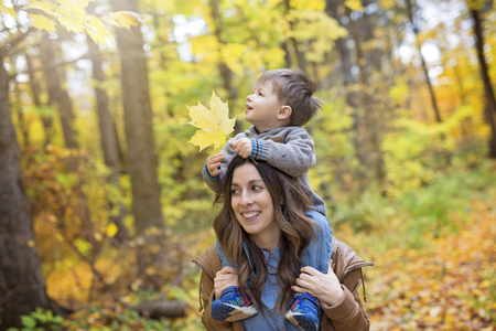 Mother with son in forest in autumnの写真素材