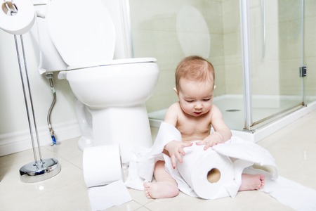 Toddler ripping up toilet paper in bathroomの写真素材