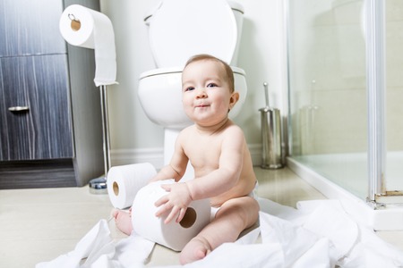 Toddler ripping up toilet paper in bathroomの写真素材