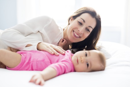 Mother and baby child on a white bed.