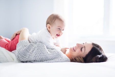Mother and baby child on a white bed.の写真素材