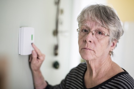 Senior woman adjusting her thermostat