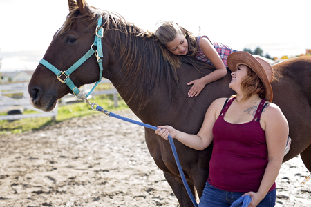 Beautiful and natural adult woman outdoors with horse  childの写真素材