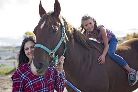 Beautiful and natural adult woman outdoors with horse childの写真素材