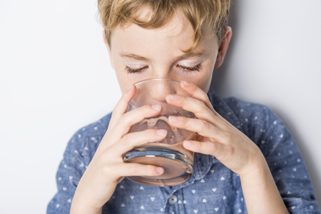 Happy smiling child drinking chocolate milk isolated on whiteの写真素材