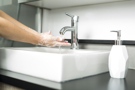 A woman washing hand on the sinkの写真素材