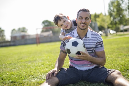 man with child playing football on fieldの写真素材
