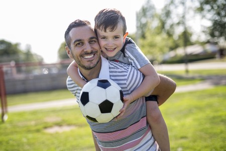 man with child playing football on fieldの写真素材
