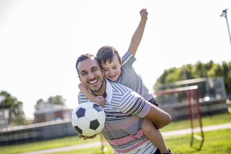 man with child playing football on fieldの写真素材