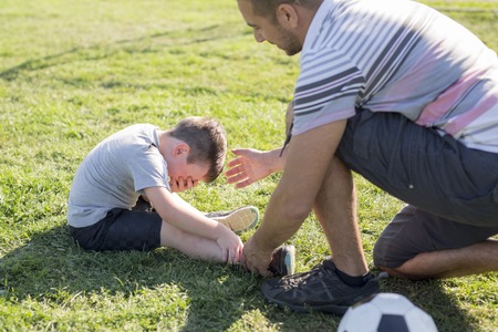 man with child playing football on field