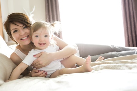 A Young happy mother with baby on bed