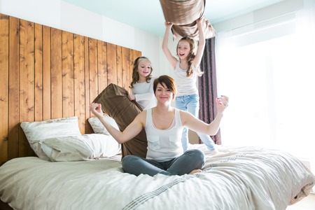 A Young mother and childs on morning yoga exercises in bedの写真素材