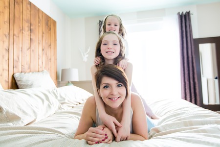 A Mother and two children in the bedroom on the bedの写真素材