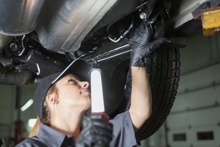 A Mechanic woman working on car in his shopの写真素材