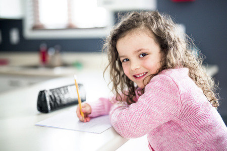 A cute girl writing with pen at the table