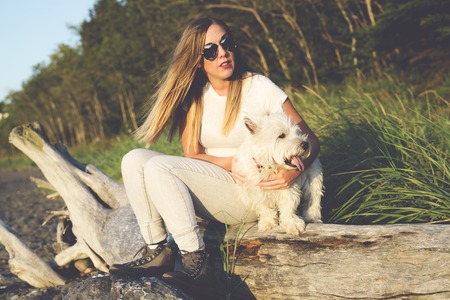 A portrait of beautiful girl keeping pretty white West Highland dogの写真素材