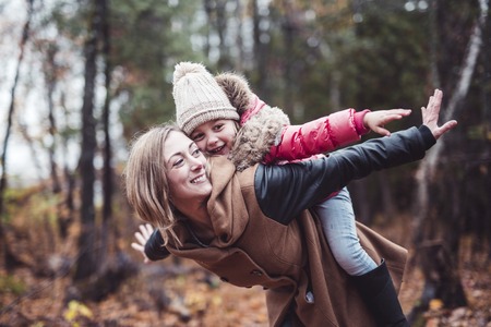 A Portrait of a smiling young woman with a little girl in autumnの写真素材
