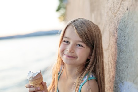 A Beautiful little girl eats ice-cream in the summerの写真素材