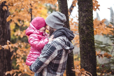 Daughter with dad walking in the autumn forestの写真素材