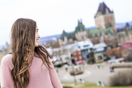 Quebec City scape with Chateau Frontenac and young teen enjoying the view.