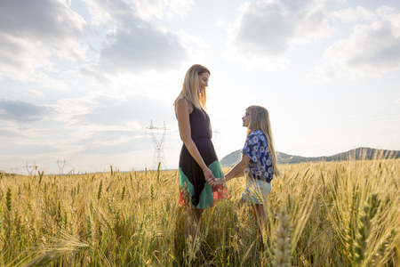 Pretty young mother with cute little daughter are happy in sunny dayの写真素材