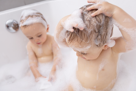Two little boys having fun with water by taking bath in bathtubの写真素材