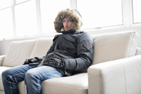 Man With Warm Clothing Feeling The Cold Inside House on the sofaの写真素材