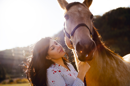 A Woman with her horse at sunset, autumn outdoors sceneの写真素材