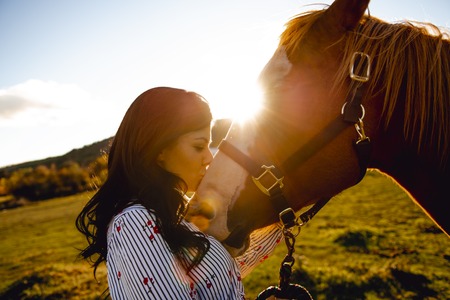 A Woman with her horse at sunset, autumn outdoors sceneの写真素材