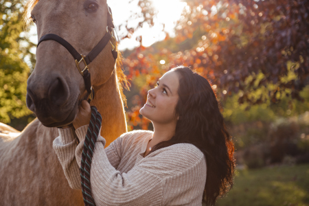 A Woman with her horse at sunset, autumn outdoors scene