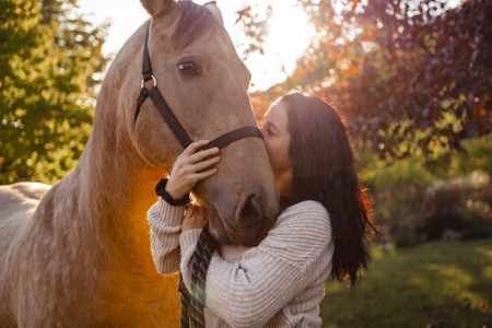 A Woman with her horse at sunset, autumn outdoors sceneの写真素材