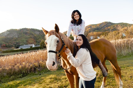 Two Womans with her horse at sunset, autumn outdoors sceneの写真素材