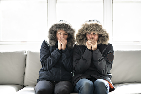 Couple have cold on the sofa at home with winter coatの写真素材