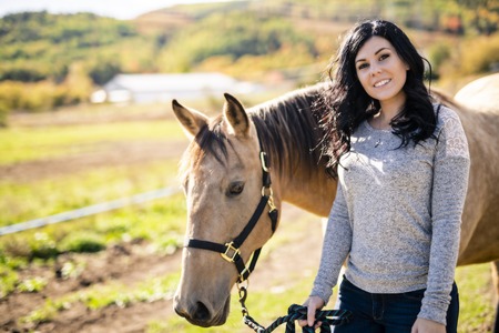 A Portrait of young beautiful woman with brown horse outdoorsの写真素材