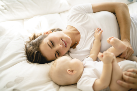 mother with baby on bed having good timeの写真素材